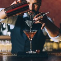 Barman is making cocktail at night club.